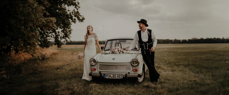 Brautpaar mit Trabant auf einer Wiese