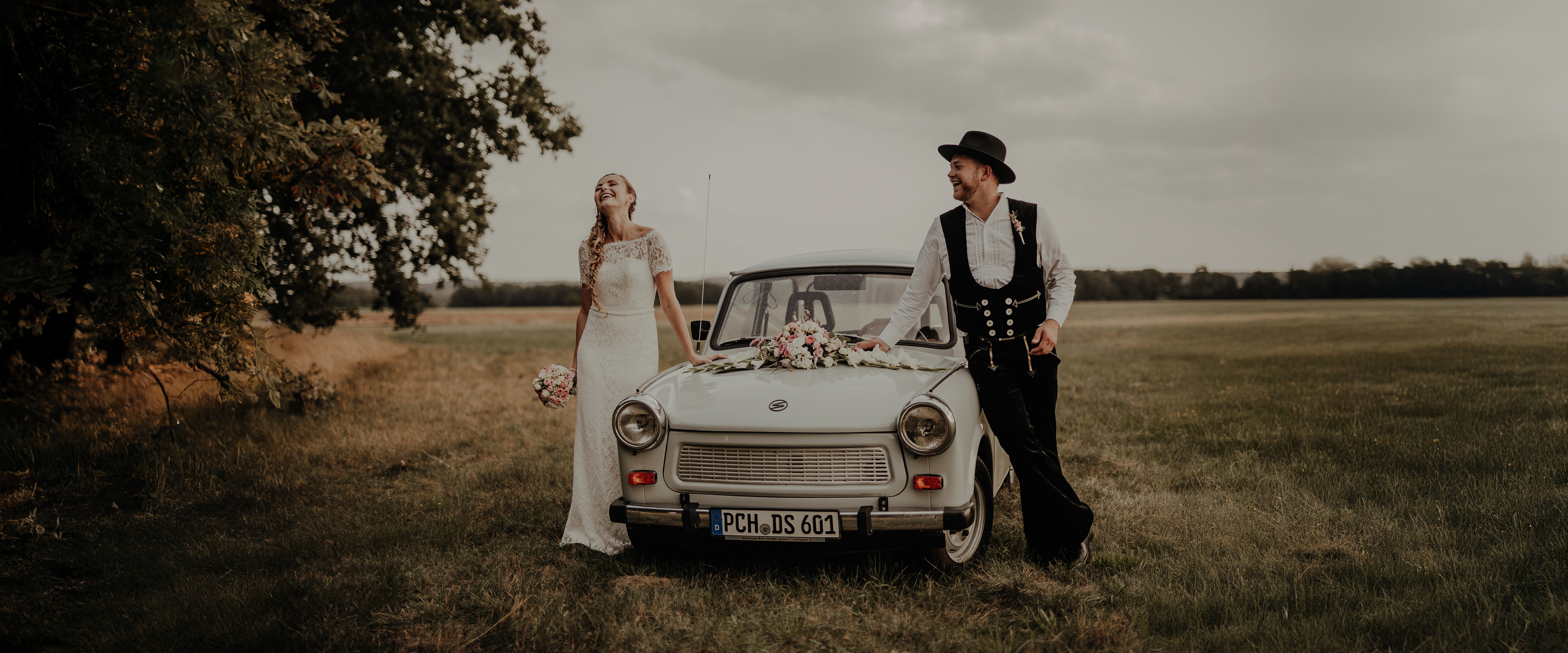 Brautpaar mit Trabant auf einer Wiese